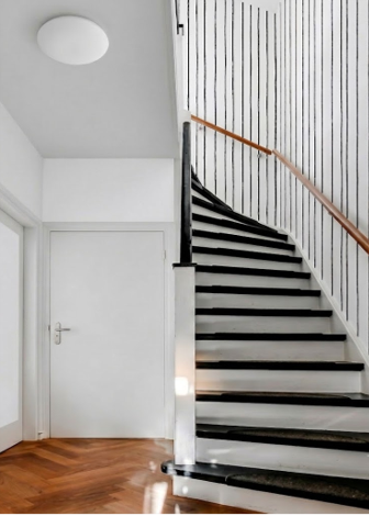 Papier peint classique noir et blanc avec des rayures qui apportent de la hauteur et de la lumière à un escalier sombre